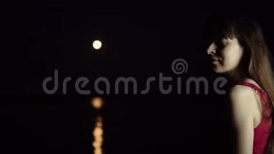 一个黑发的年轻女子欣赏河中倒影的红月。